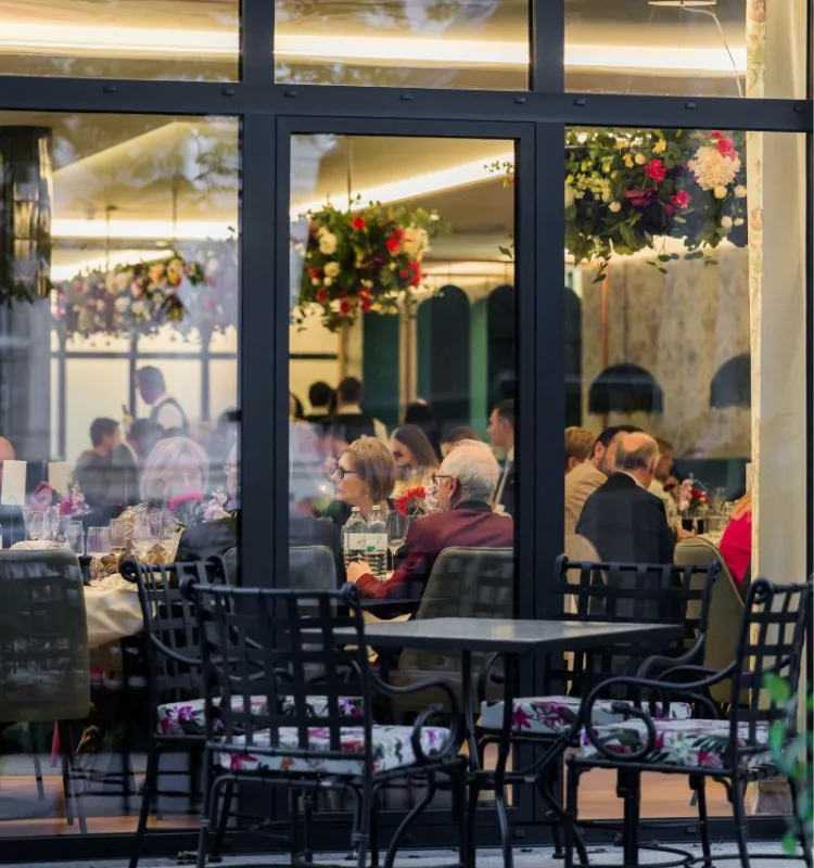 Blick durch die Glasfront auf Gäste bei einer festlichen Veranstaltung im Restaurant des Grand Elisabeth in Bad Ischl.