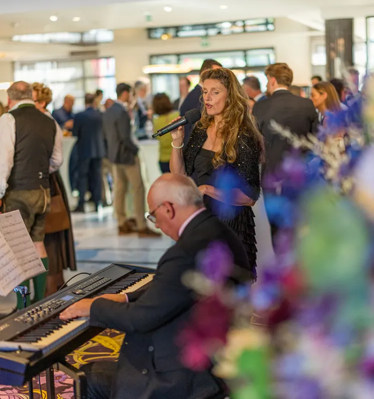 Singer and pianist at an evening event at Grand Elisabeth Bad Ischl with formally dressed guests in the background
