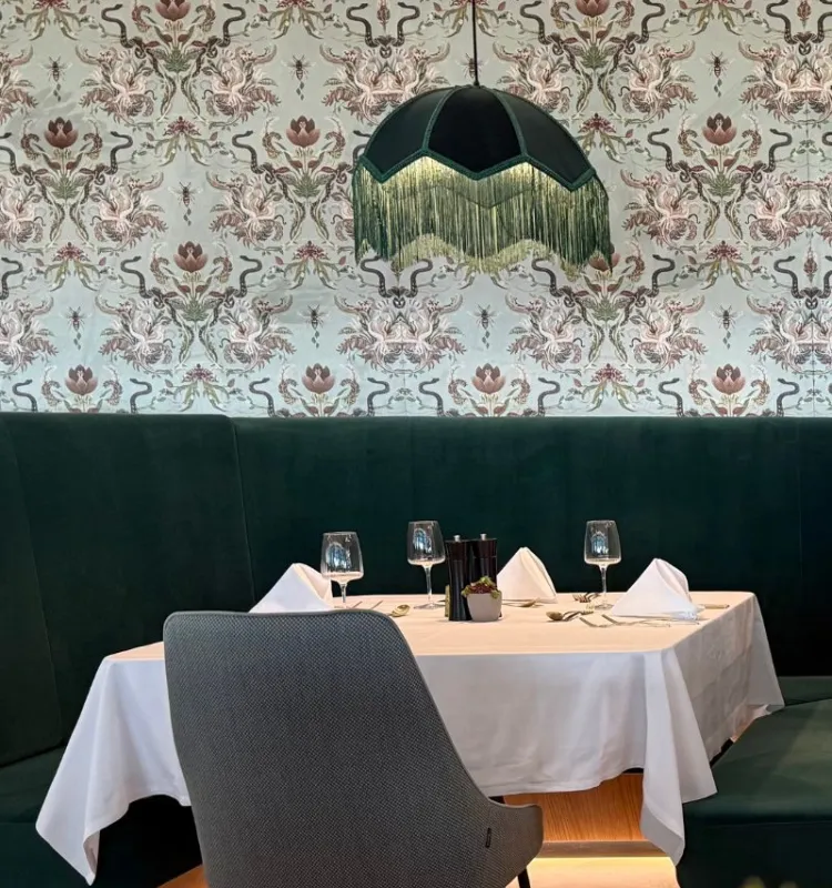 Elegant gedeckter Tisch im Restaurant des Grand Elisabeth in Bad Ischl mit stilvoller Einrichtung und floraler Tapete.