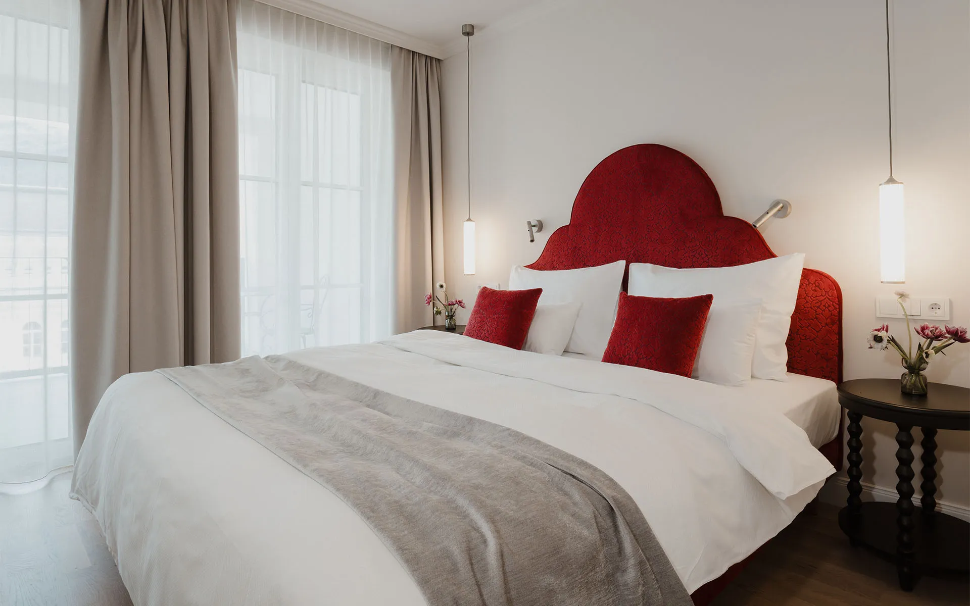 Klassisches Doppelzimmer im Hotel Bad Ischl mit Balkon, rotem Kopfteil und Tageslicht
