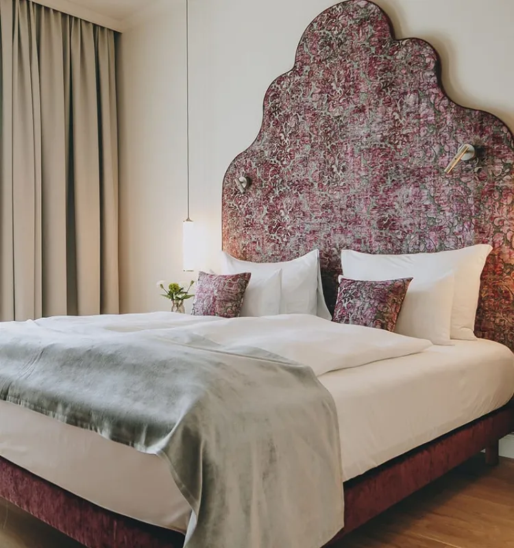 Designhotel Kaiserstadt: opulentes Bett mit Kissen und Designleuchte