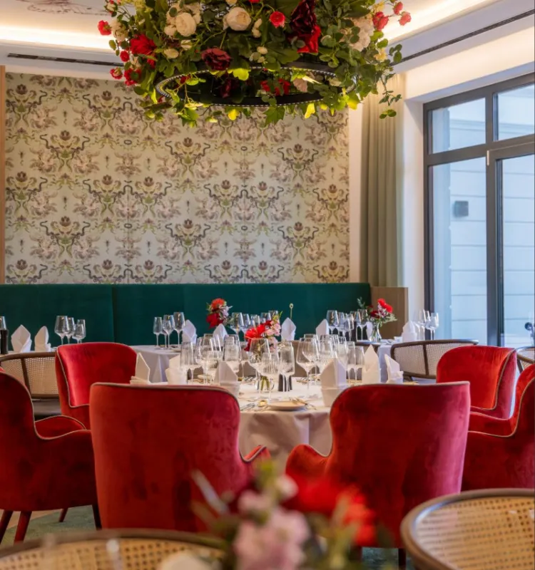 Elegant restaurant at Grand Elisabeth Bad Ischl with red velvet chairs, set tables and floral chandelier