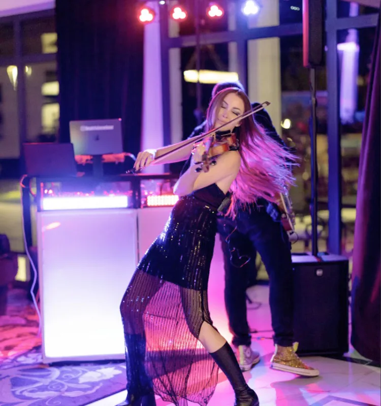 Violinist Beatrix Löw-Beer passionately playing the violin at an evening event at the Grand Elisabeth Bad Ischl, surrounded by colourful stage lighting in pink and red.