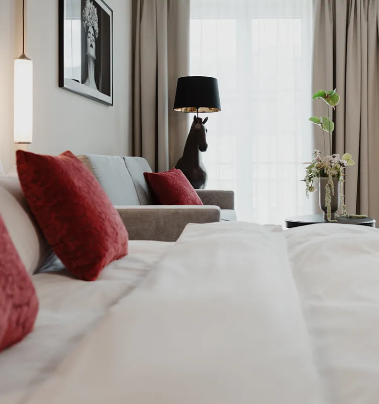 Designhotel Kaiserstadt: eleganter Schlafbereich mit roten Akzenten und moderner Stehlampe