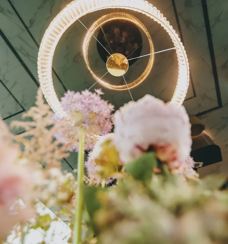 Portrait of the ceiling chandelier in the Grand Elisabeth Hotel with numerous vacation offers, framed by floral decoration in the foreground