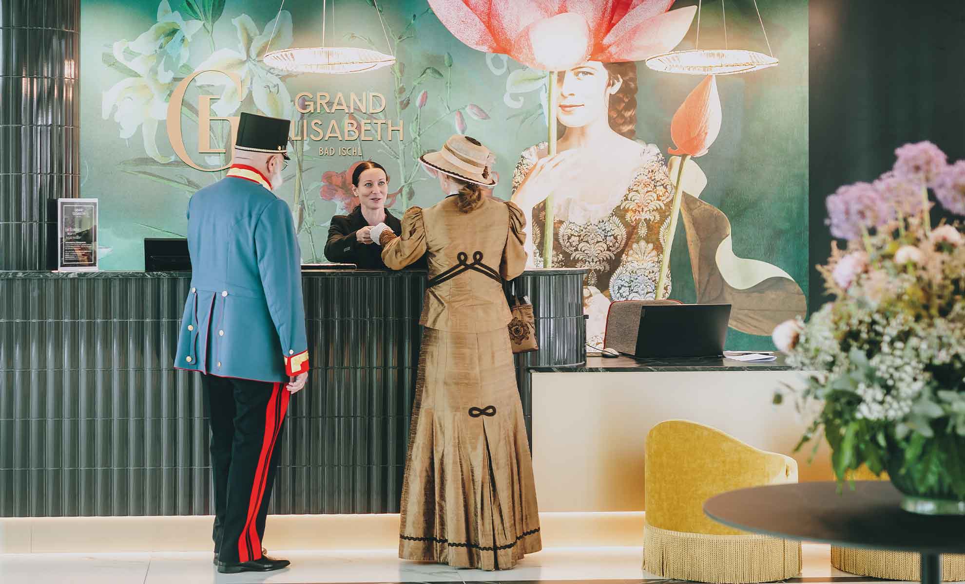 Porträt von Gästen in historischer Kleidung an der Rezeption im Grand Elisabeth Hotel in Bad Ischl.