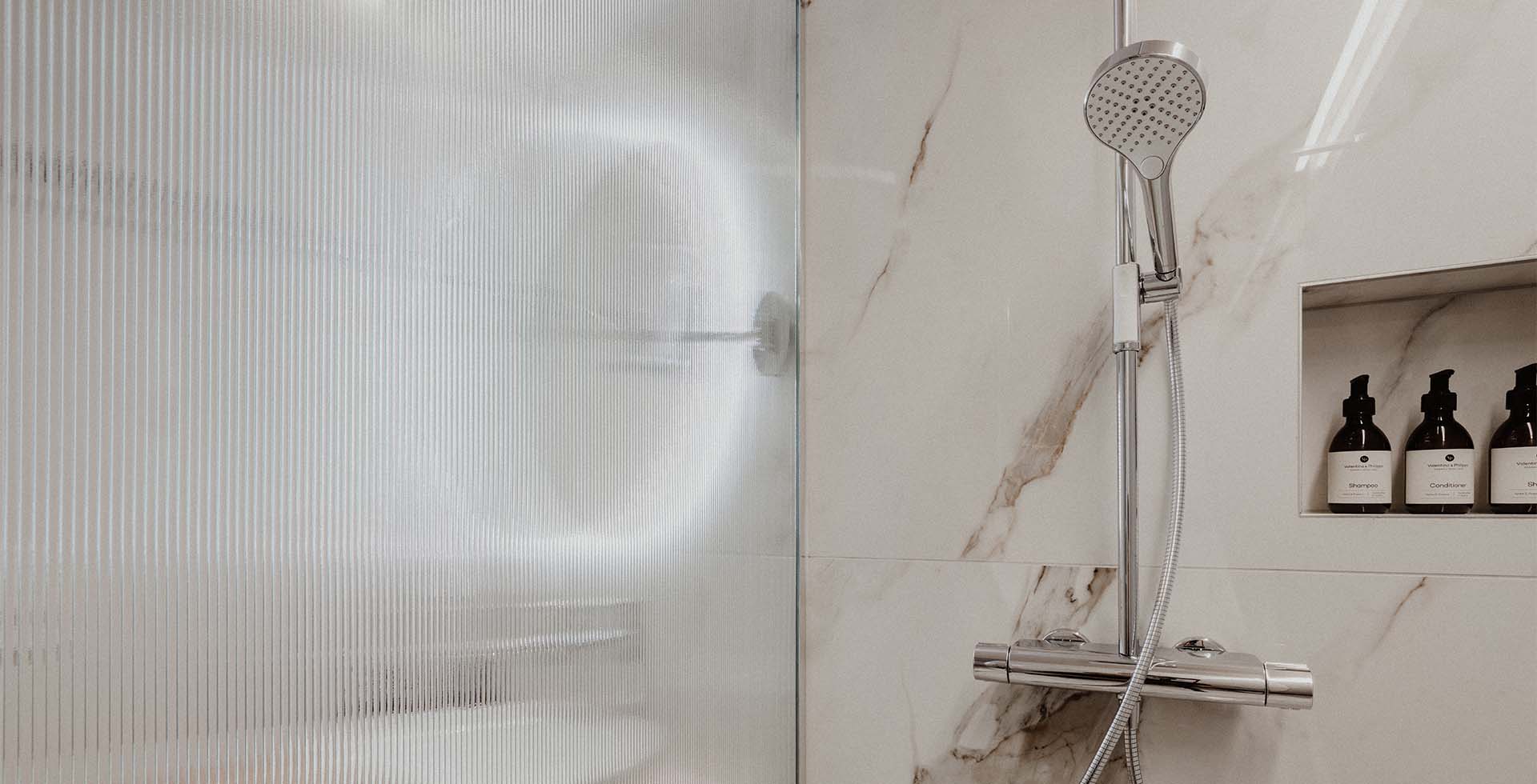 Regendusche im stilvollen Bad mit eingelassenem Regal und Fliesen