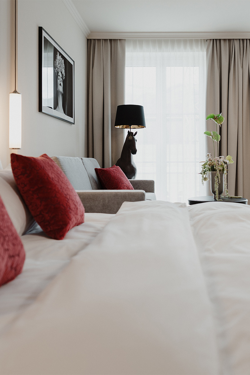 Designhotel Kaiserstadt: eleganter Schlafbereich mit roten Akzenten und moderner Stehlampe