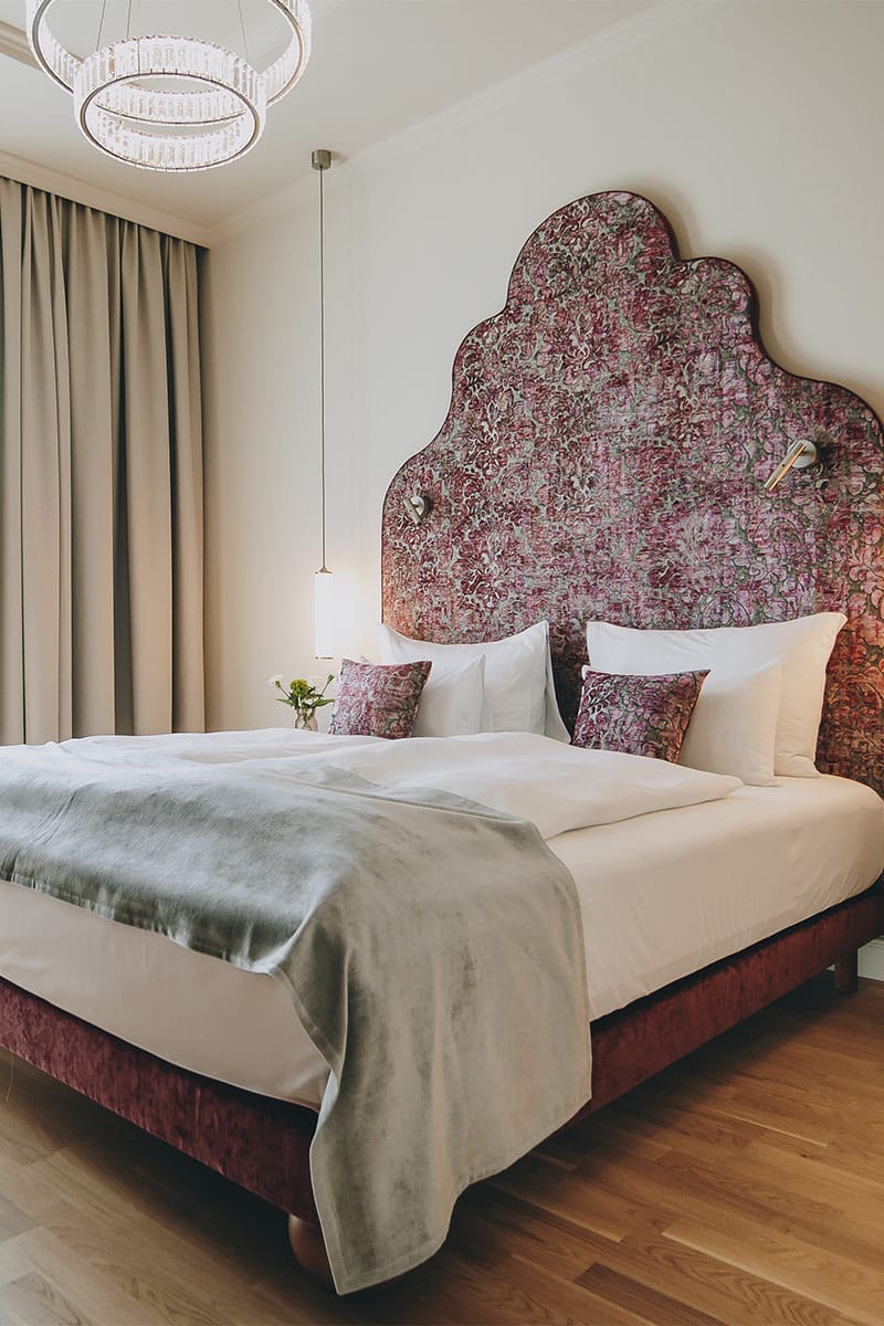 Designhotel Kaiserstadt: opulentes Bett mit Kissen und Designleuchte