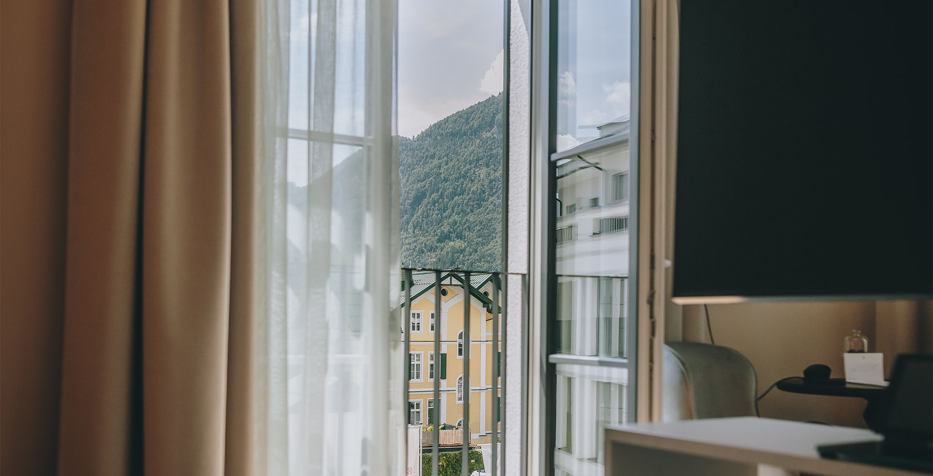 Fensterblick im Designhotel Grand Elisabeth mit Sicht auf Bergpanorama und historische Architektur