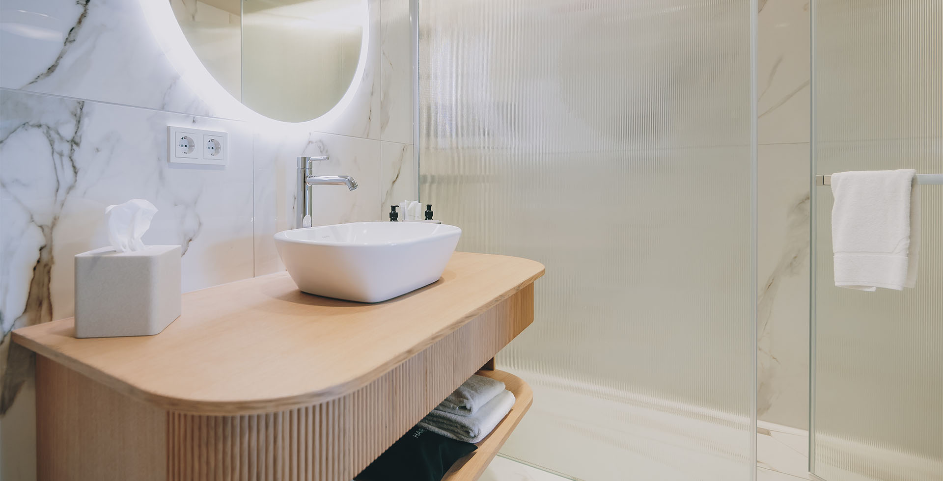 Helles Badezimmer im Wellnesshotel Bad Ischl mit stilvollem Interieur und Holzwaschtisch