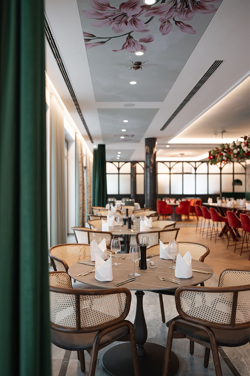 Grand Liberté Restaurant im Grand Elisabeth mit floralem Deckendekor und gedeckten Tischen