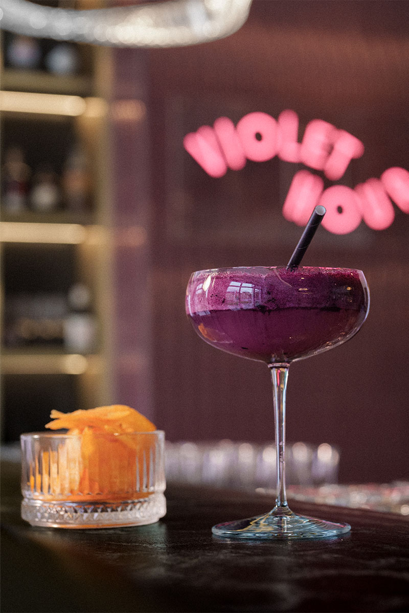 Fruchtiger Cocktail im Wellnesshotel Grand Elisabeth vor violettem Barhintergrund mit Neonschrift