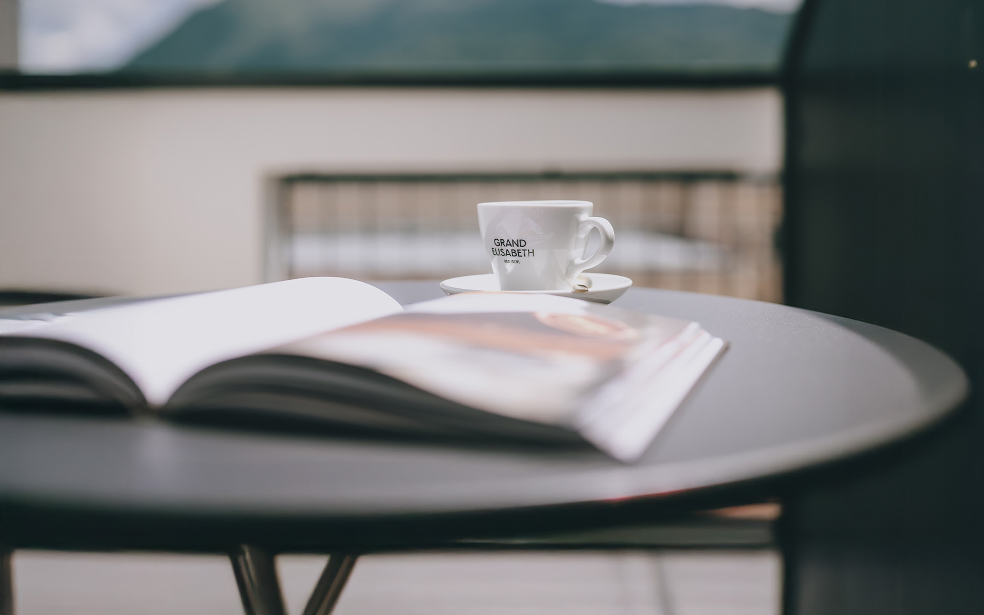 Entspannter Moment mit Tasse Kaffee auf der Terrasse im Wellnessurlaub im Grand Elisabeth mit Bergen im Hintergrund
